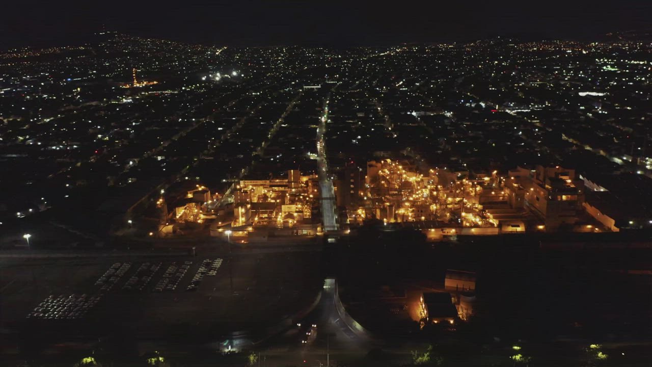 Industrial plant glowing at night beside a city